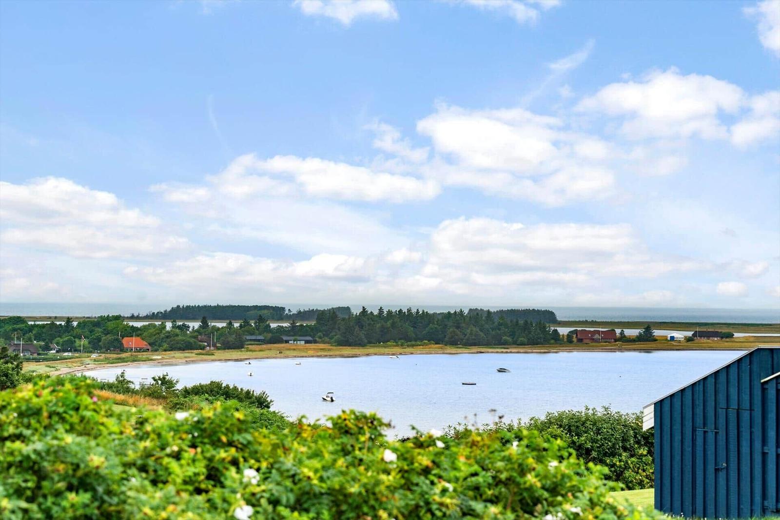 Blick auf einen See mit Booten und grüner Landschaft im Hintergrund.
