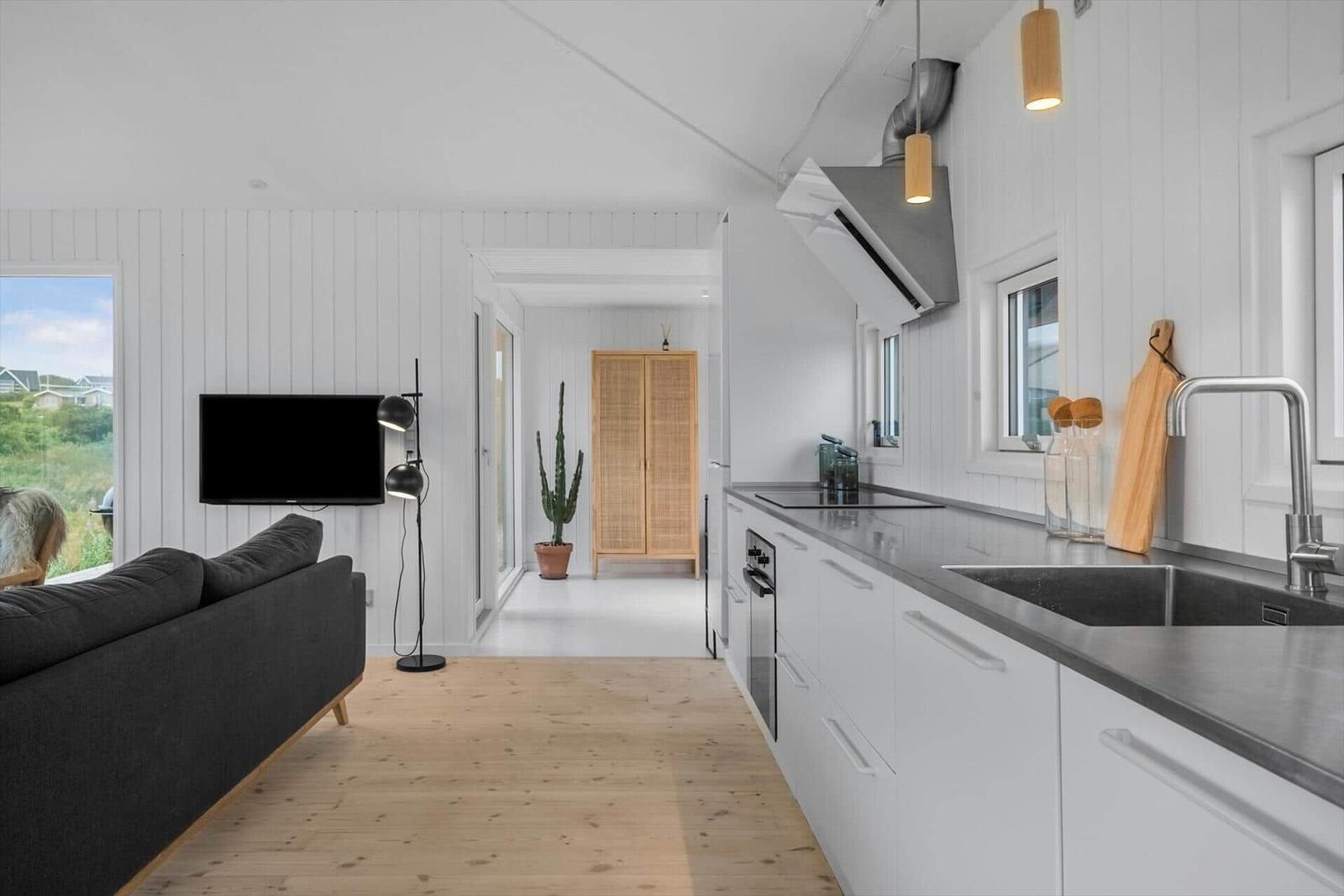 Küche und Wohnbereich mit Sofa, Fernseher und Holzboden.