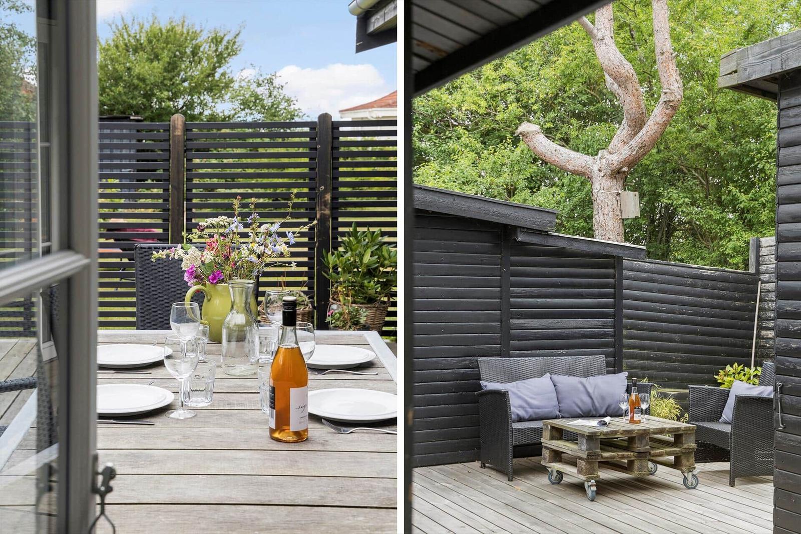 Deck with table, chairs, and flowers. Sofa with cushions and wooden table.