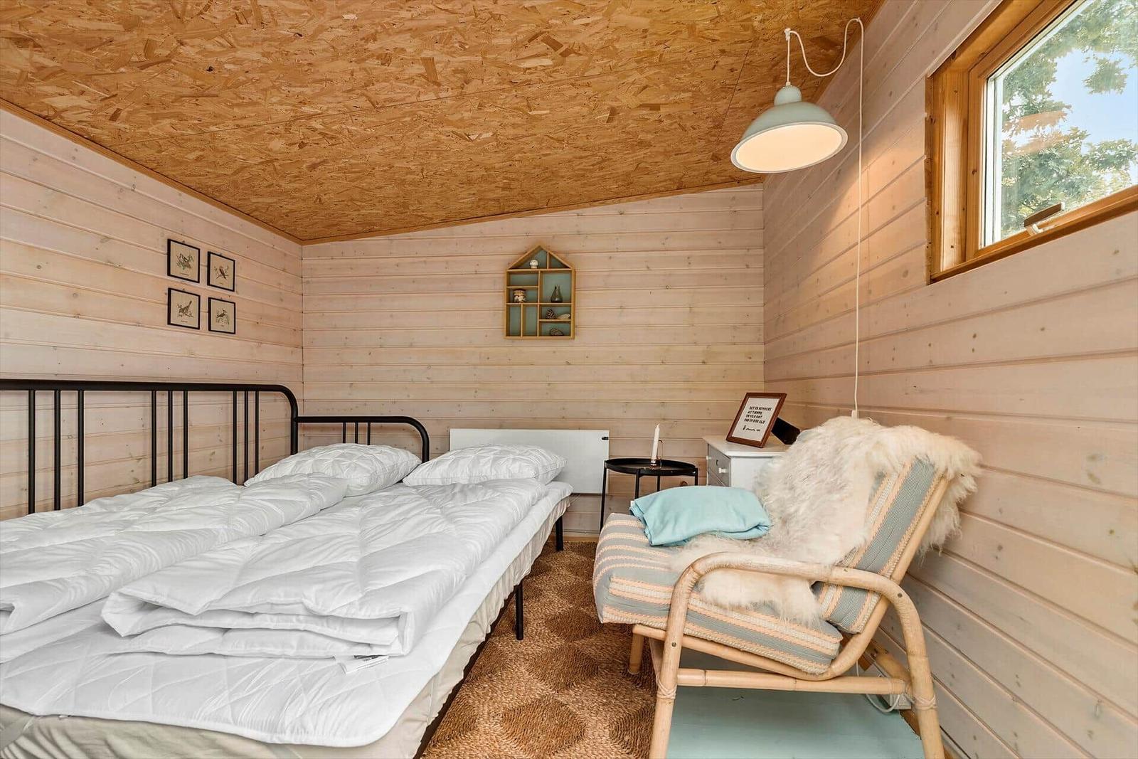 Bedroom with bed, chair, and wood-paneled walls.