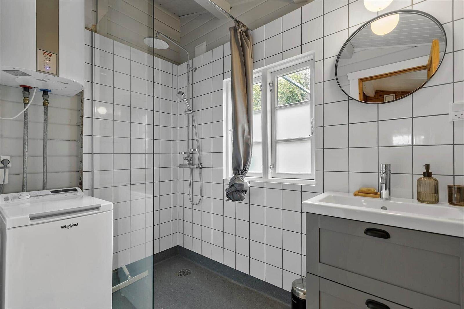 Bathroom with shower, sink, and window.