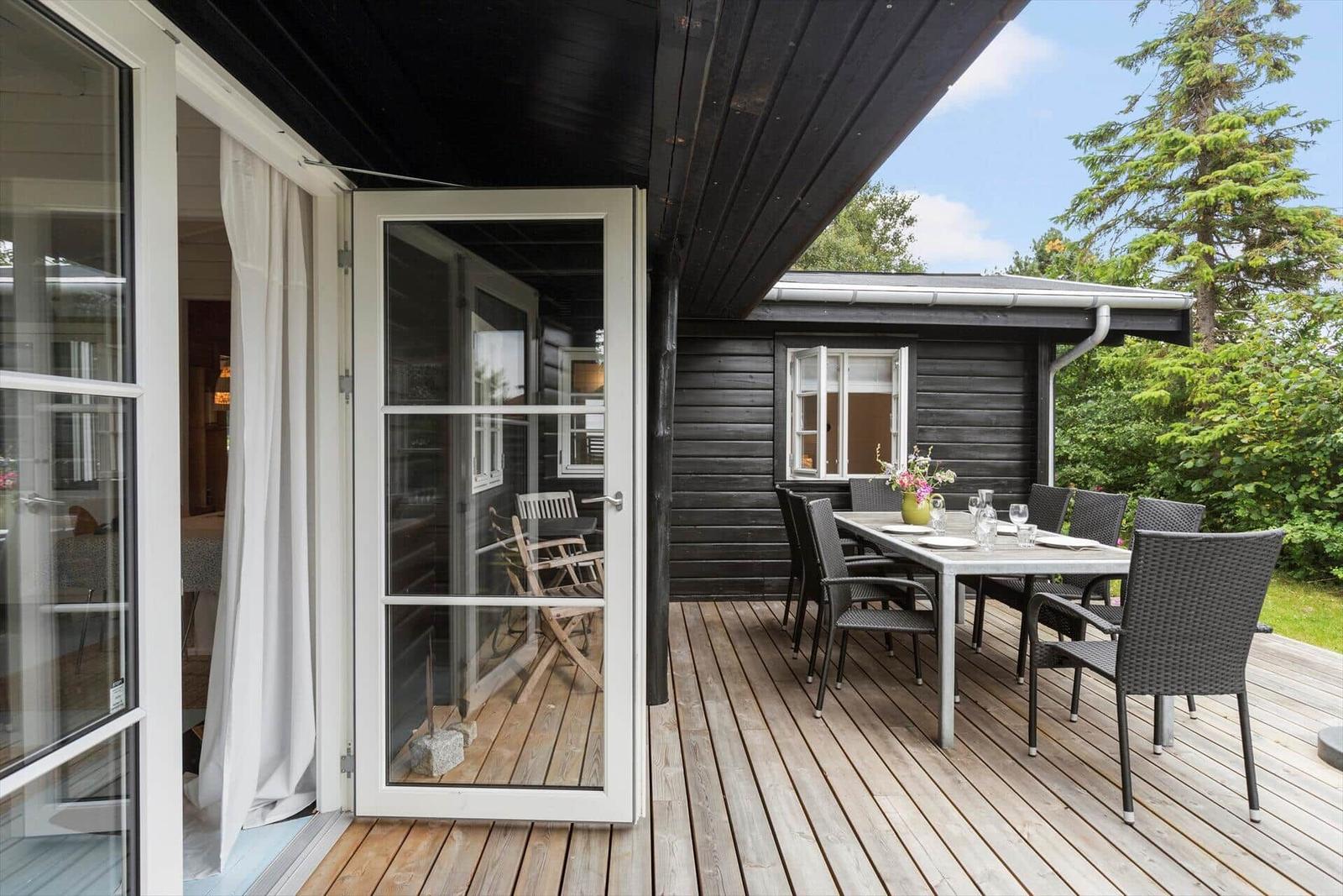 Deck with table and chairs, access to house via glass door.