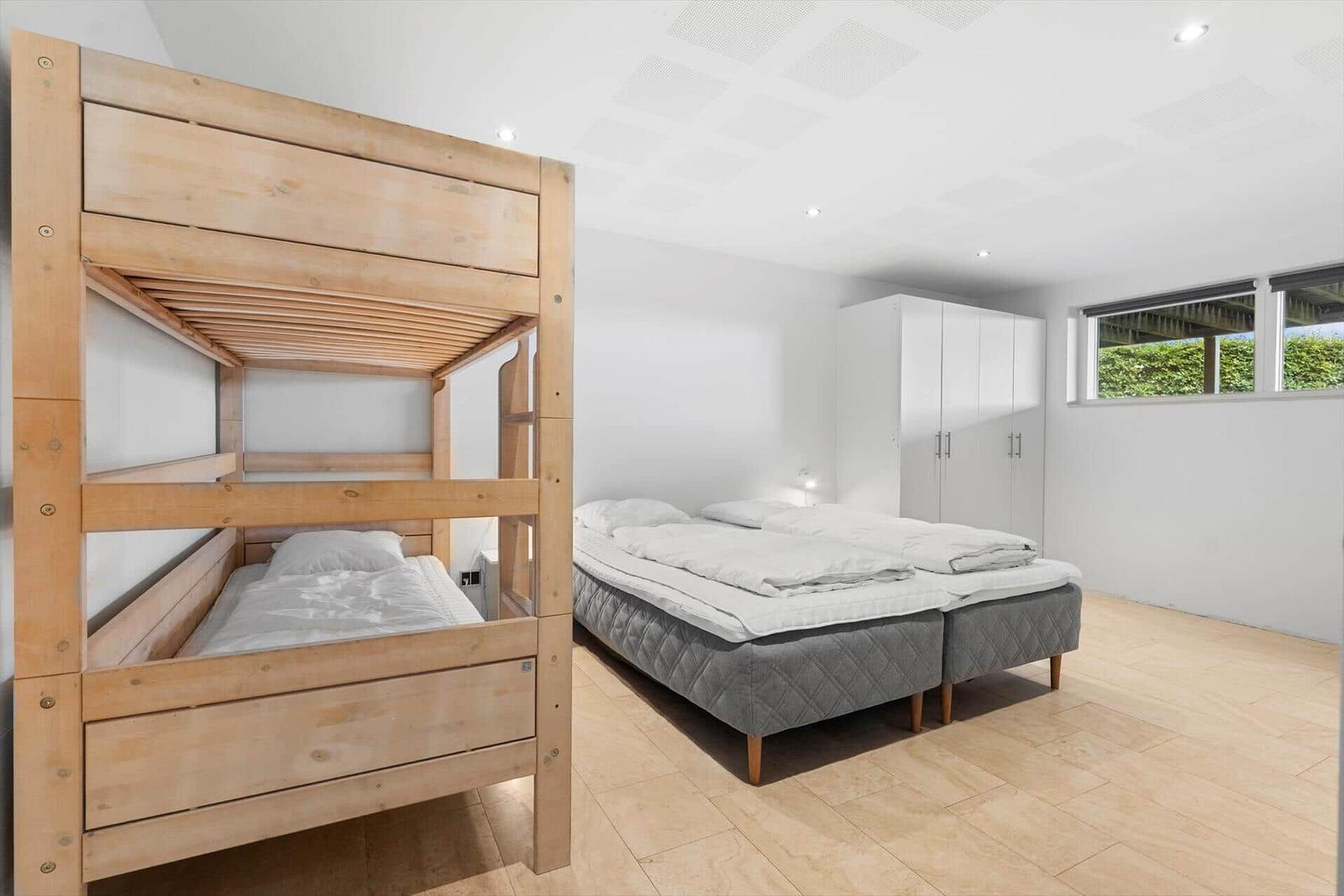 Zimmer mit Doppelbett und Hobbelbett, weiße Wände und Holzboden.