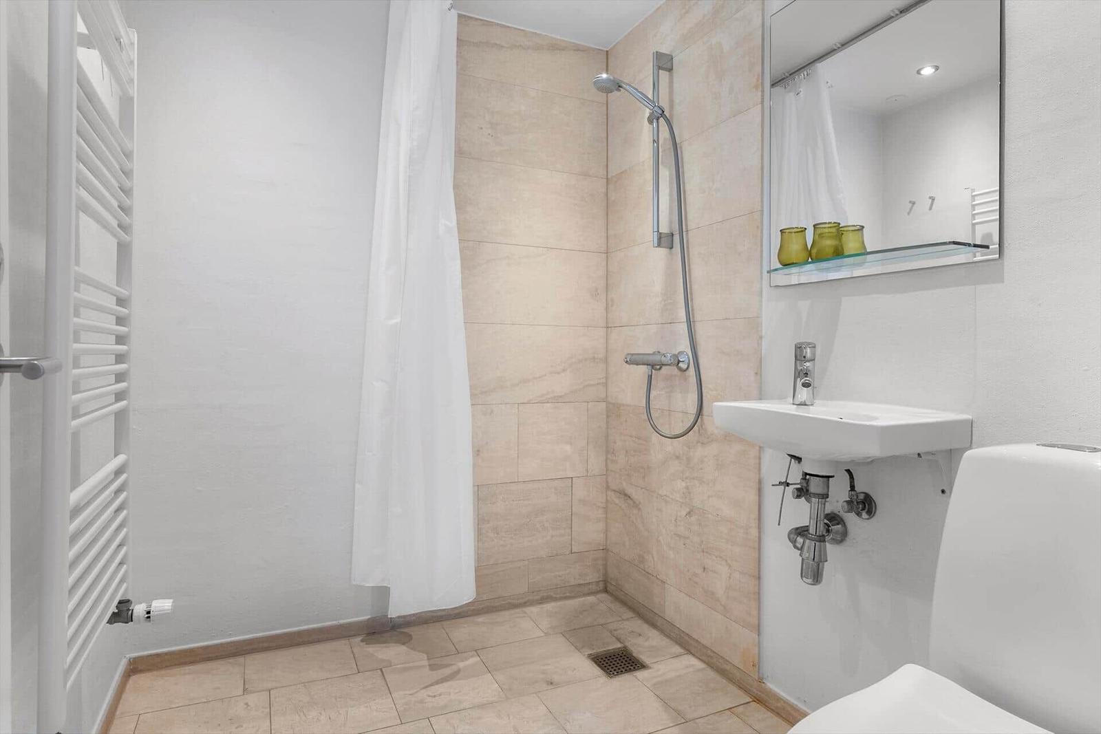 Badezimmer mit Dusche, Waschbecken und Toilette.