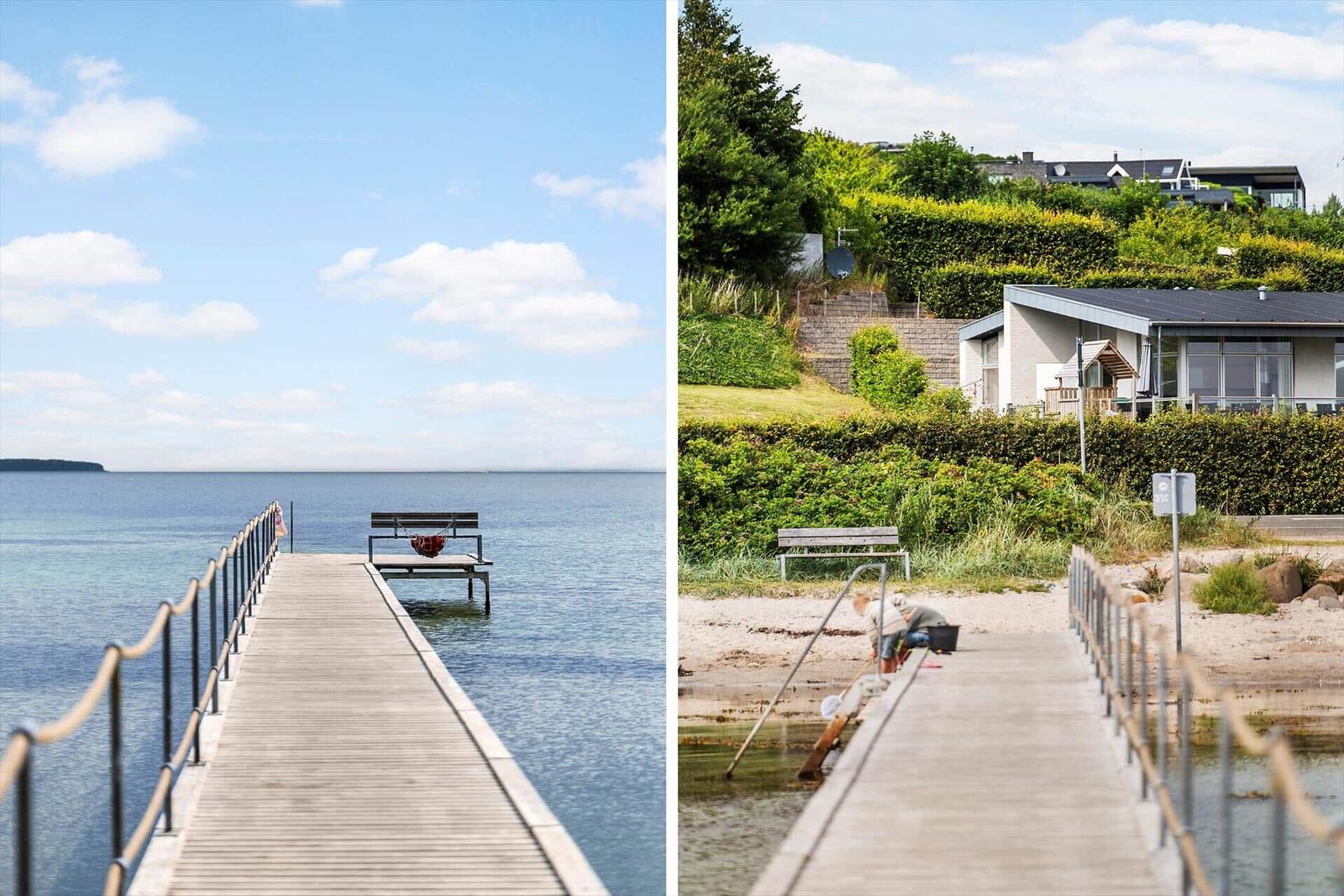 Holzsteg mit Bank führt ins Wasser. Im Hintergrund moderne Villa mit Garten.