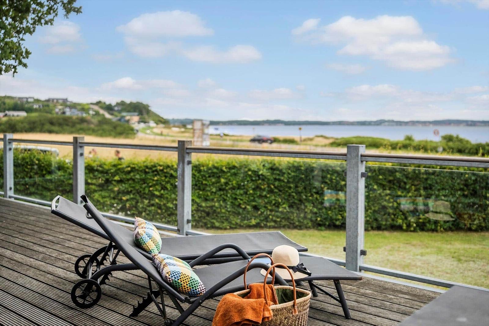 Terrasse mit Liegestühlen und Blick auf Wasser und Hügel.