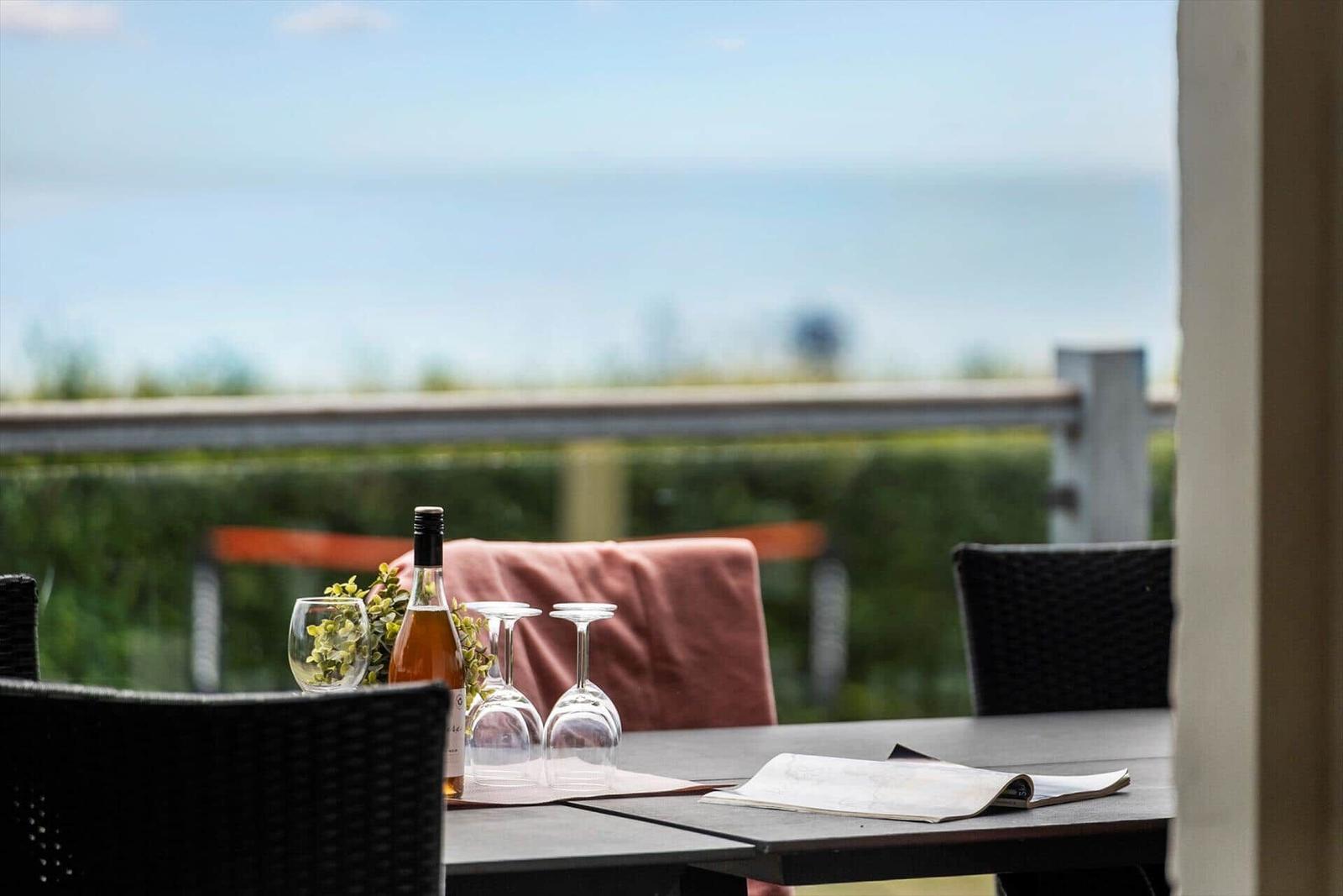 Terrasse mit Tisch, Weinflasche und Blick auf die Landschaft.