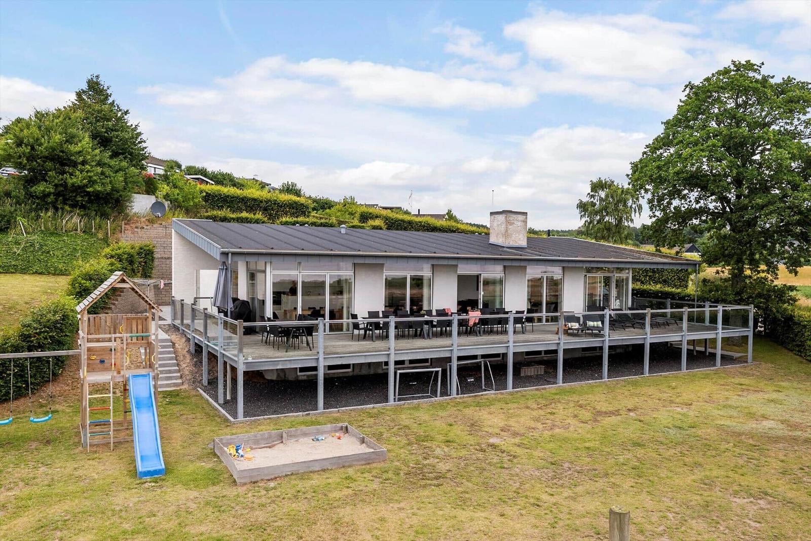 Moderne Villa mit großem Balkon, Spielplatz und Sandkasten im Garten.
