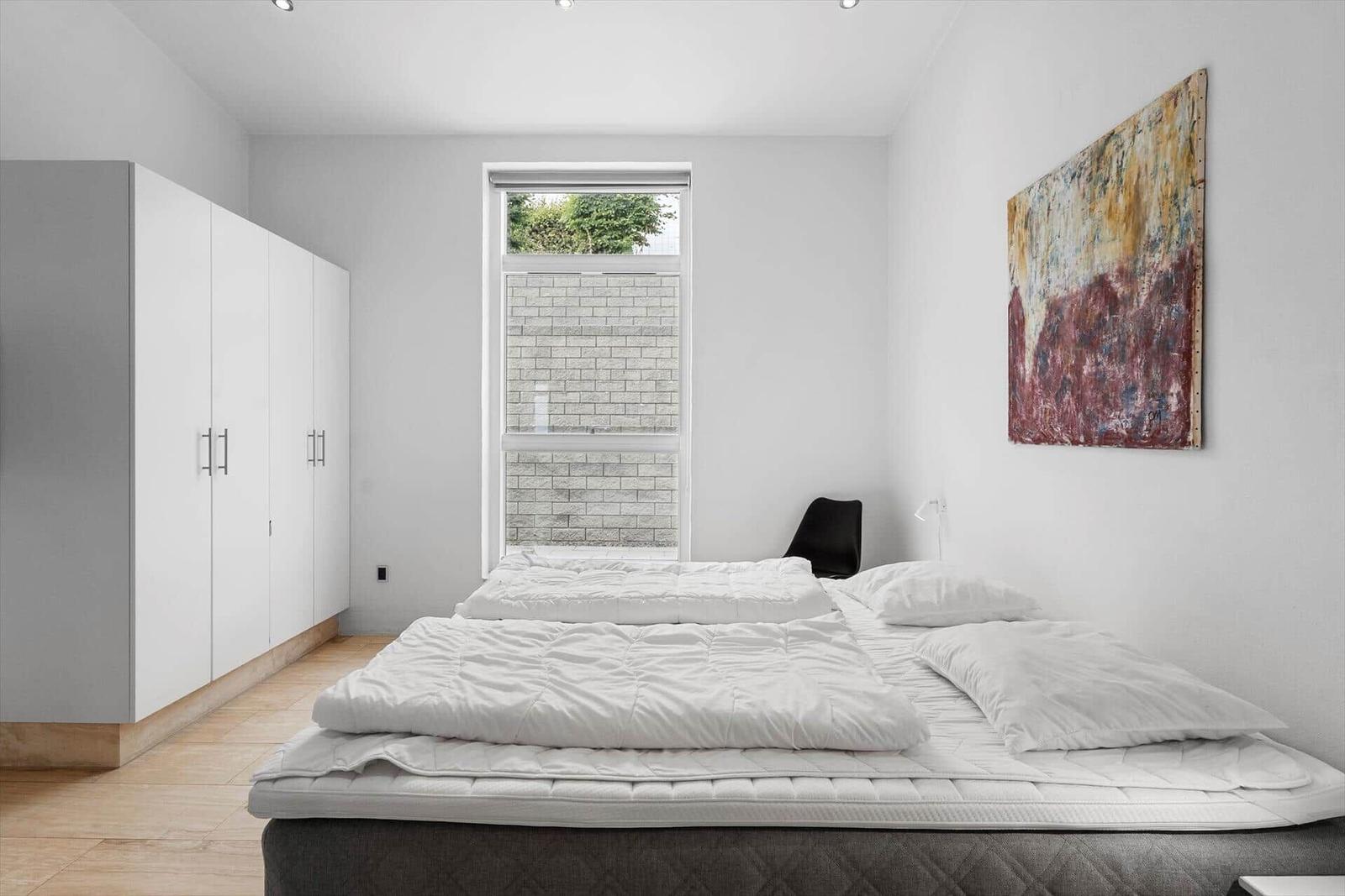 Schlafzimmer mit Bett, Kleiderschrank und Fenster