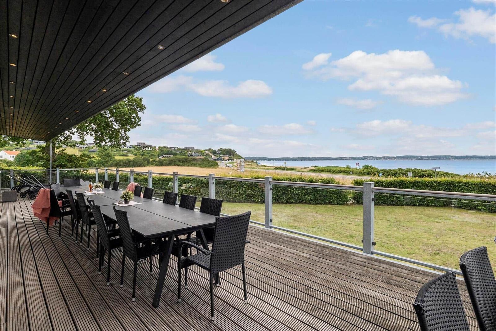 Terrasse mit Tisch und Stühlen bietet Blick auf See und Landschaft.