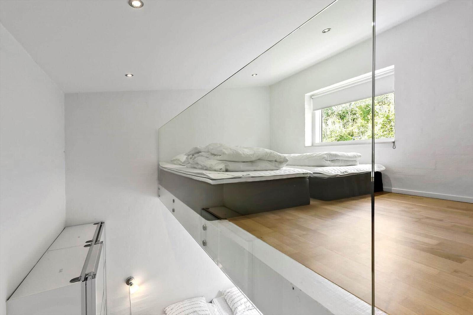 Schlafzimmer mit Hochbett, Spiegelwand und Holzboden. Fenster mit Blick auf Grün.