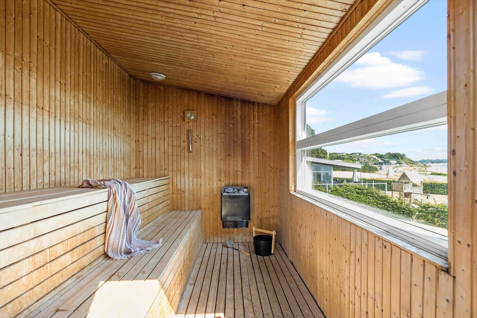 Sauna mit Holzvertäfelung und großem Fensterblick auf Außenbereich.