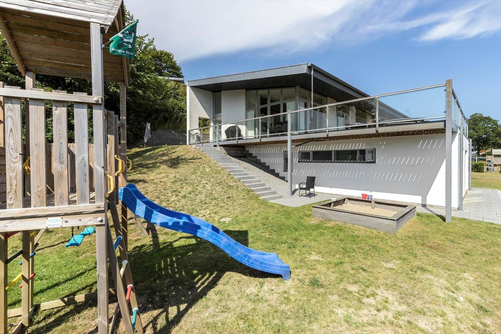 Moderne Villa mit Spielplatz und Sandkasten im Garten.