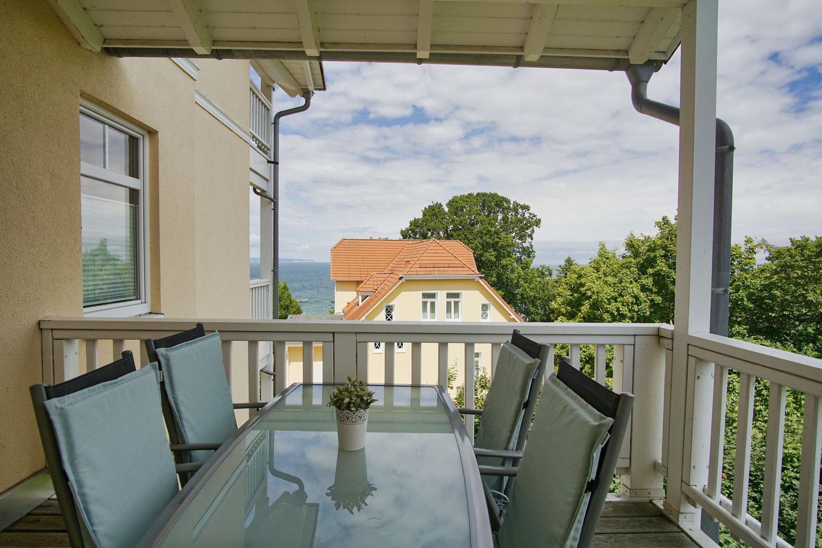 Terrasse mit Tisch und Stühlen. Blick auf Haus und Meer.
