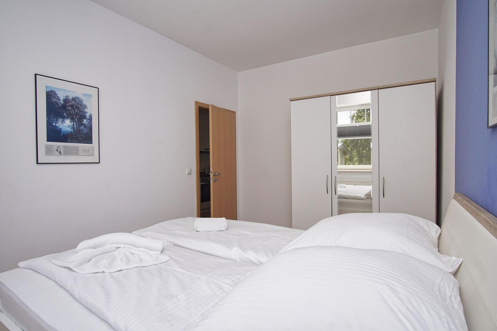 Schlafzimmer mit Doppelbett, Kleiderschrank und Bild an der Wand.