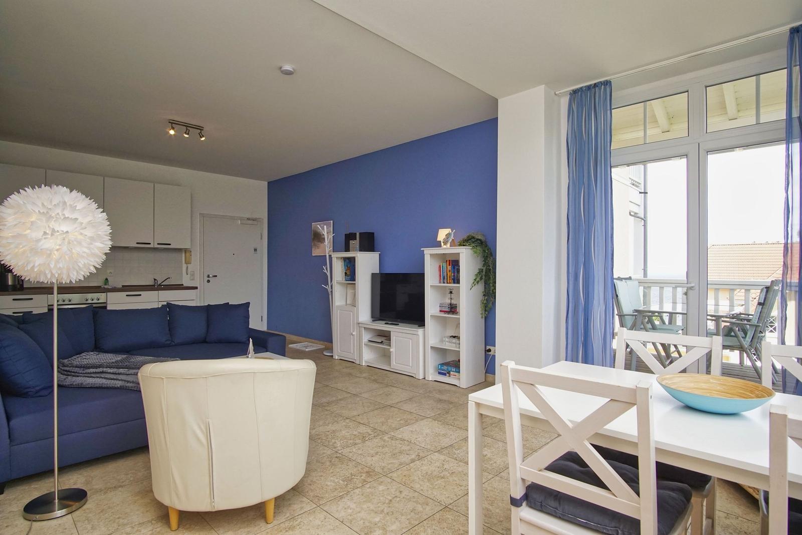Wohn- und Essbereich mit blauer Wand, Sofa und Blick auf Balkon.