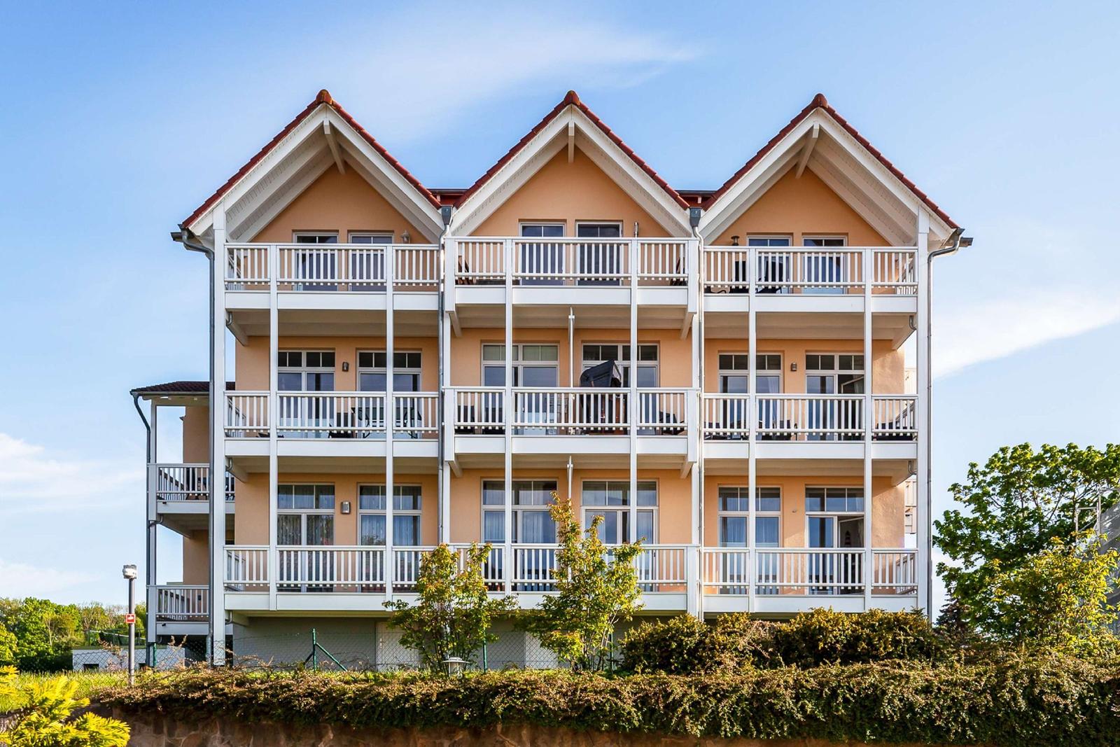 Drei-Stöckiges Haus mit weißen Balkonen und rotem Dachziegel