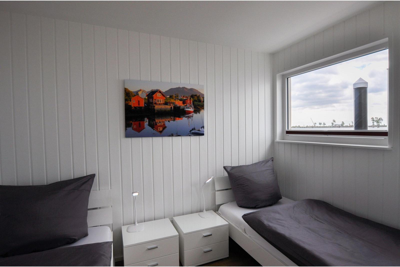 Zwei Einzelbetten mit Nachttischen und Fensterblick auf einen Turm.