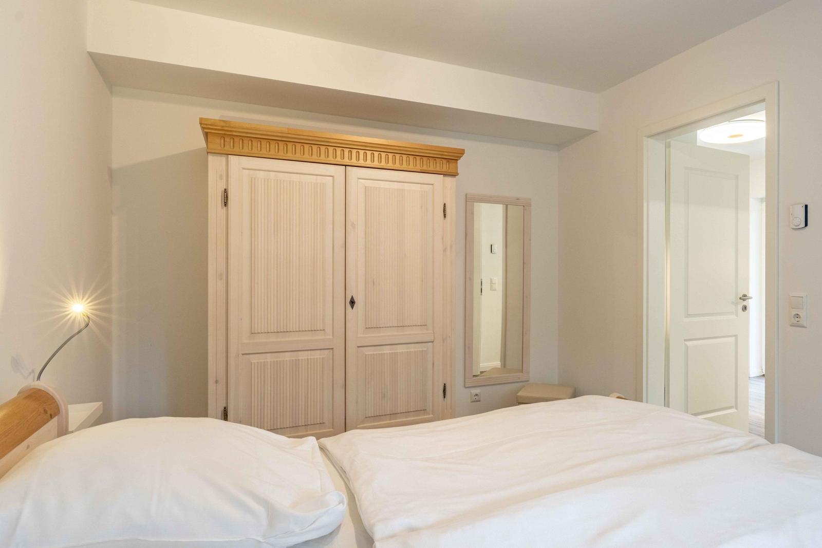 Schlafzimmer mit Bett, Kleiderschrank und Spiegel.