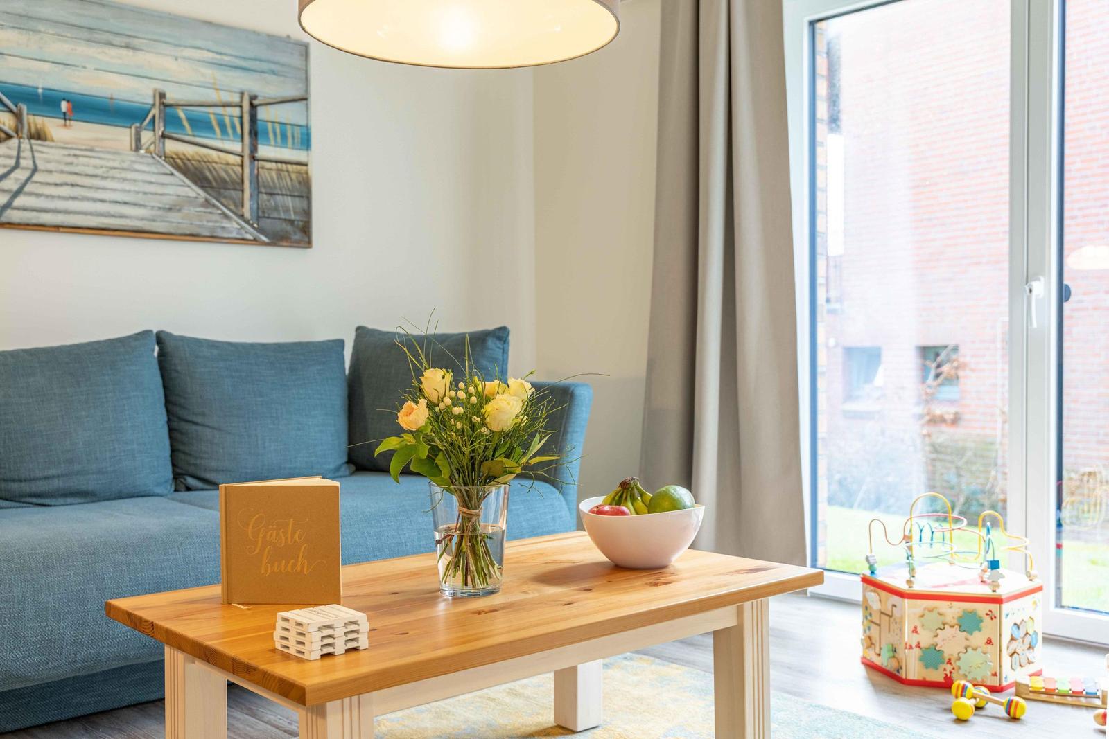Ein Wohnzimmer mit blauem Sofa, Holztisch und Spielzeug.