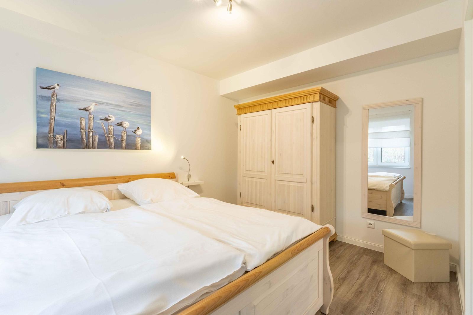 Schlafzimmer mit Bett, Kleiderschrank und Wandbild mit Möwen.