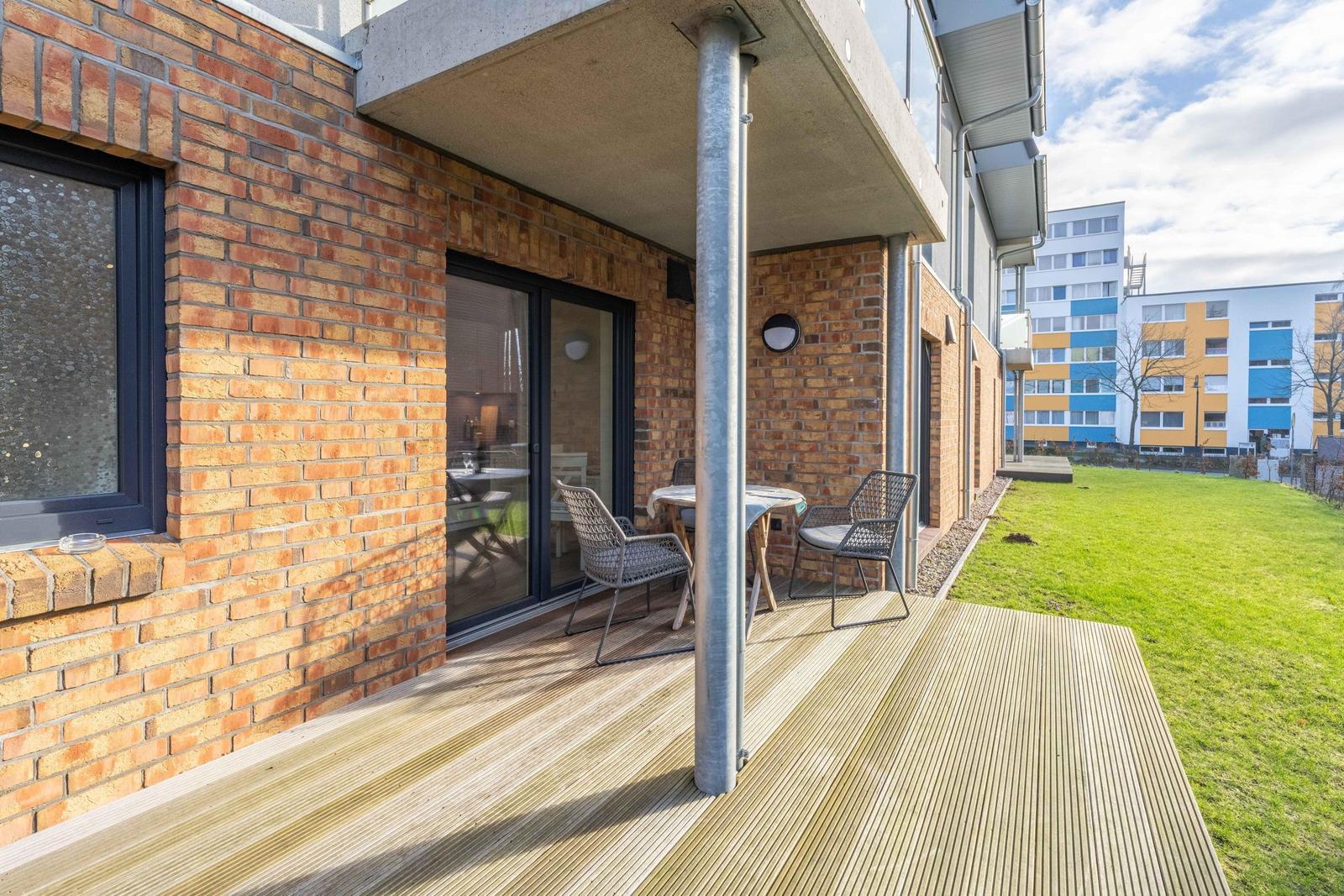 Terrasse mit Tisch und Stühlen neben einem Haus mit Backsteinfassade.