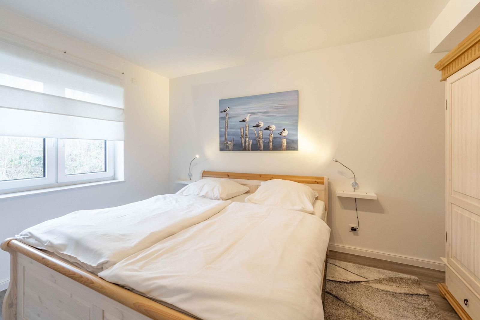 Schlafzimmer mit Doppelbett, Wandbild und Kleiderschrank.