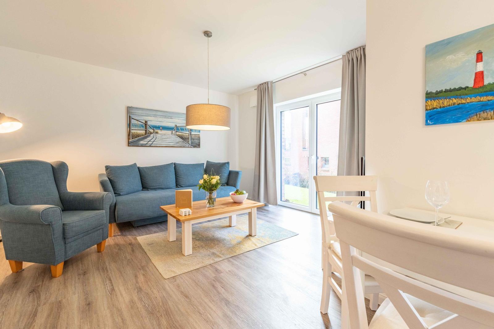 Wohn- und Essbereich mit Sofa, Sessel, Tisch und Fenster.