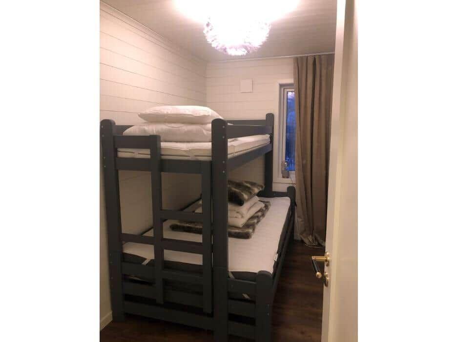 Zimmer mit Doppelstockbett, Fenster und Holzboden.