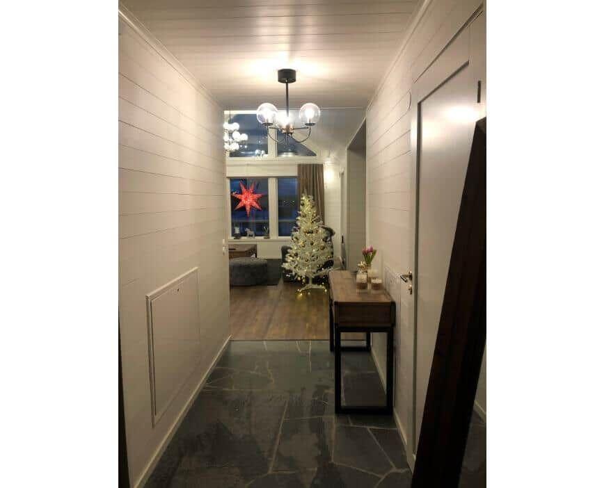 Flur mit Holzwand, Steinboden und Weihnachtsbaum im Hintergrund