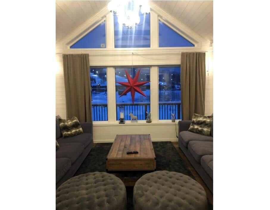 Wohnzimmer mit zwei Sofas, Holztisch und roter Sterndekoration an der Wand.