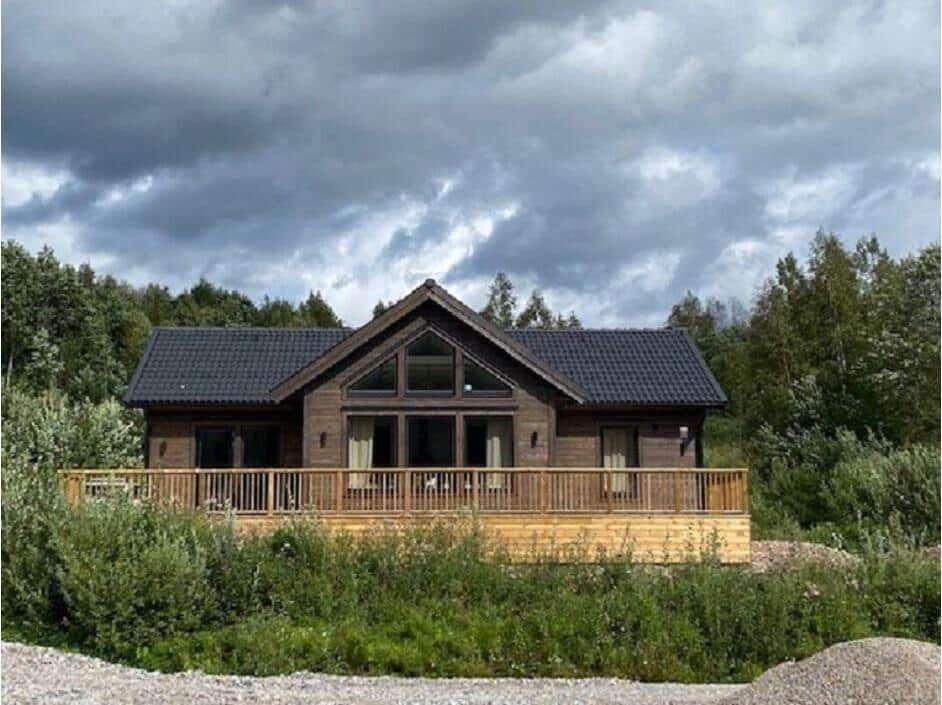 Holzhaus mit Balkon und großem Fenster unter bewölktem Himmel