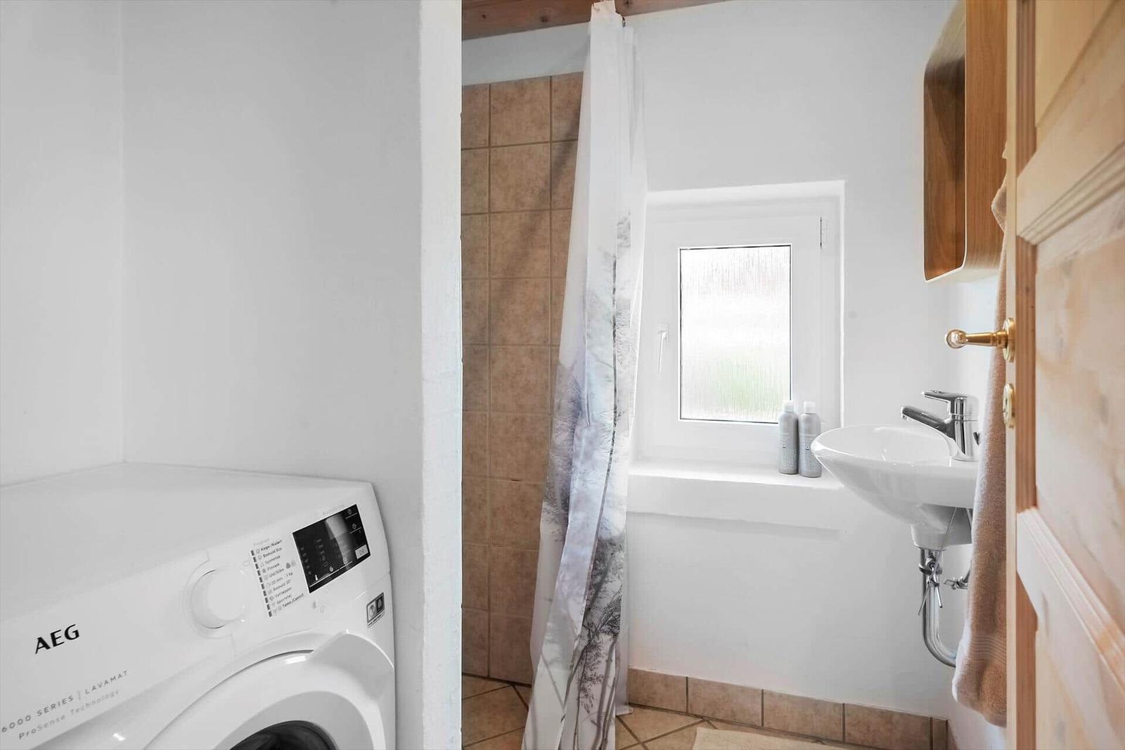 Badezimmer mit Waschmaschine, Dusche und Waschbecken