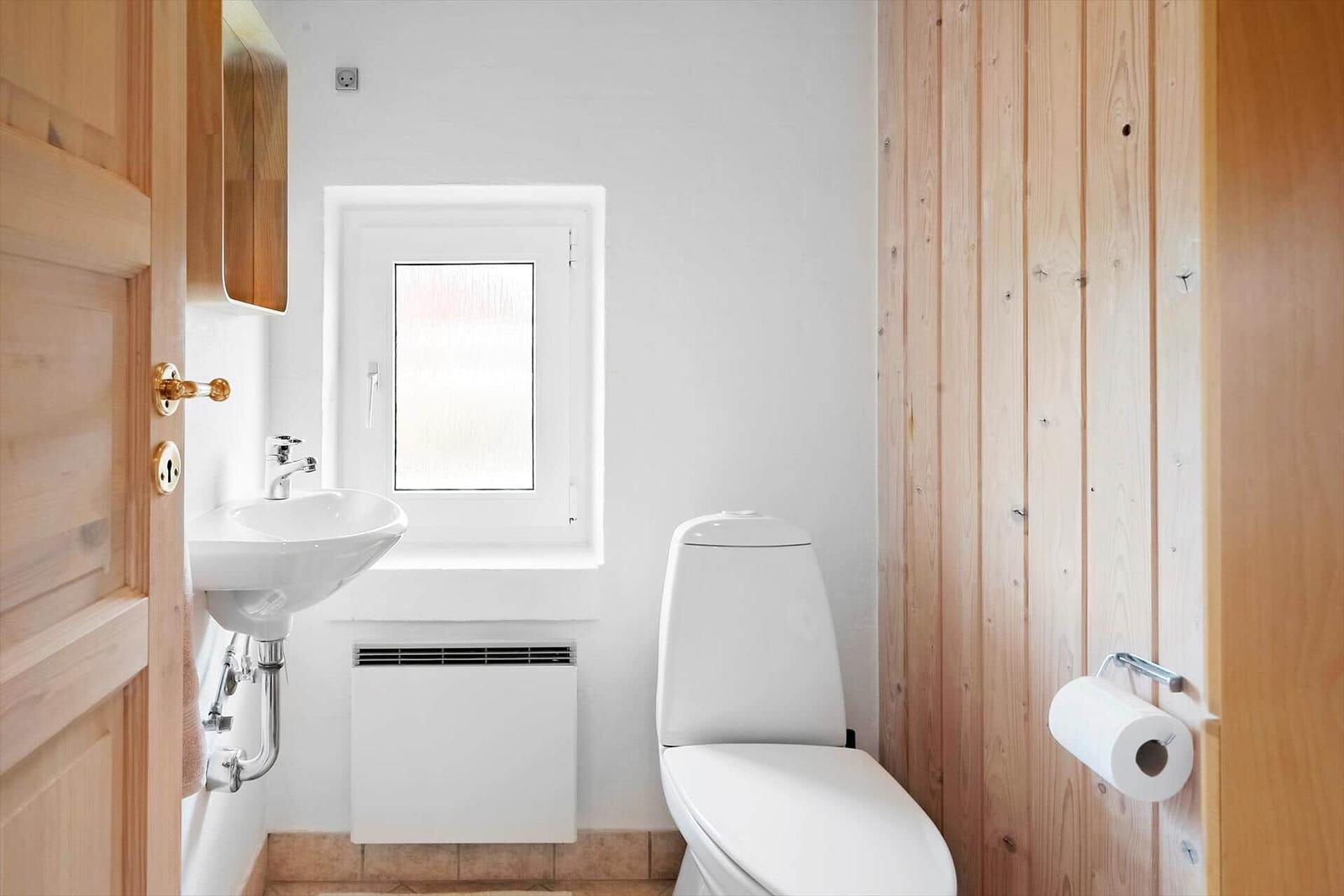 Badezimmer mit Toilette, Waschbecken und Fenster.