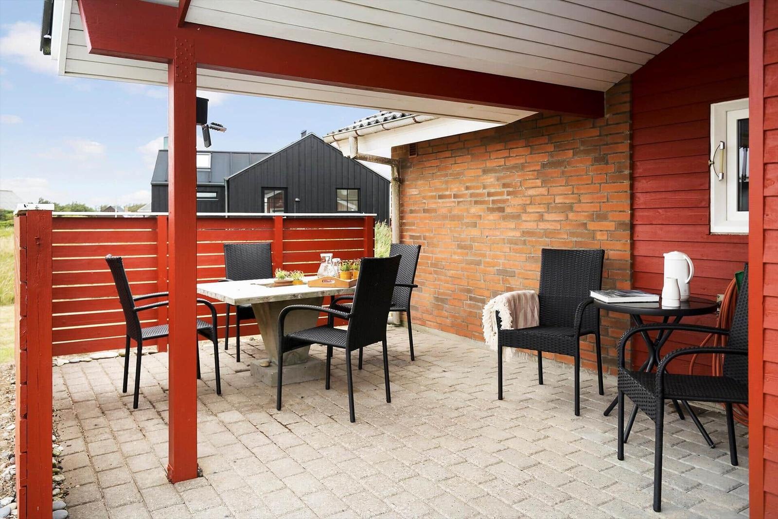 Terrasse mit Tisch, Stühlen und Sitzgelegenheiten unter Pavillon.