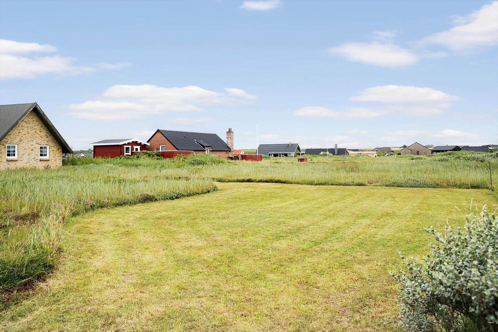 Grüner Rasenplatz mit Blick auf mehrere Häuser im Hintergrund.