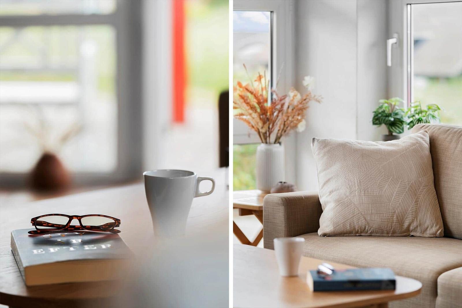 Tisch mit Tasse, Brille und Buch. Sofa mit Kissen und Pflanzen.