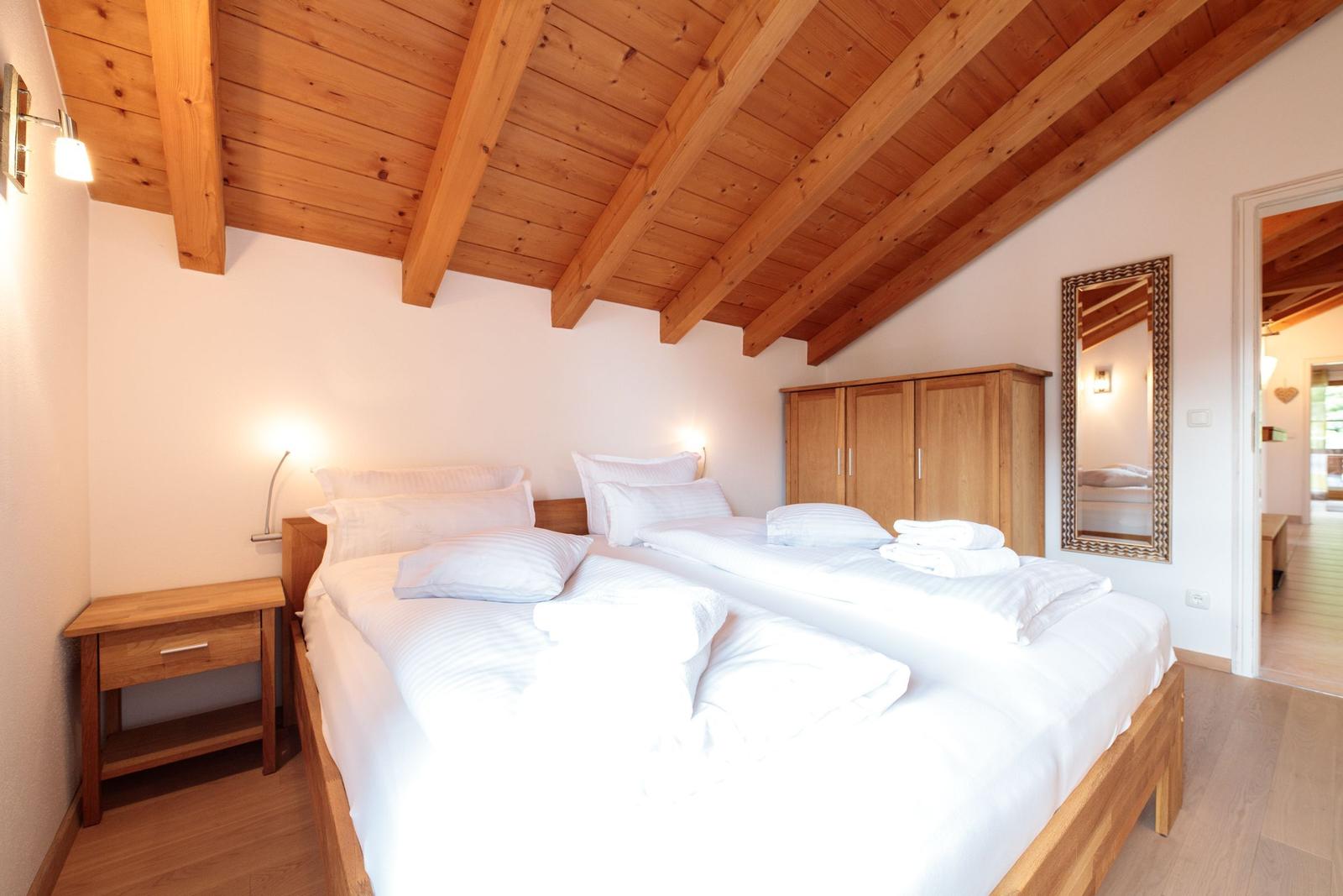 Schlafzimmer mit Doppelbett, Holzboden und Holzdecke mit Balken.