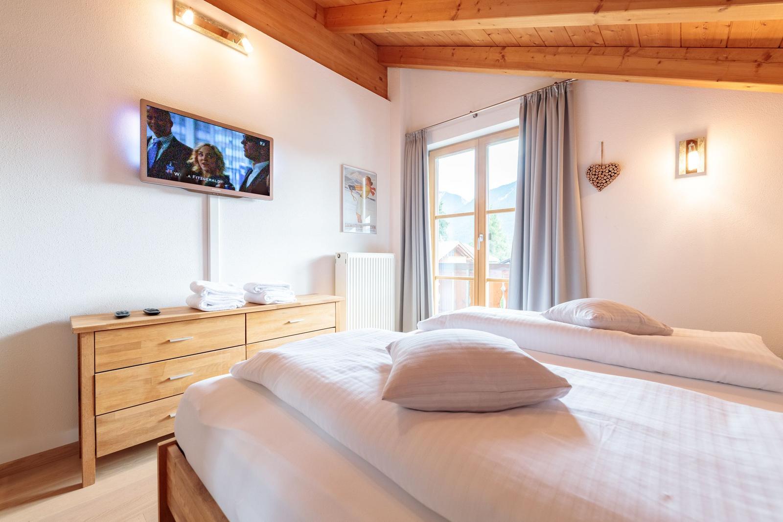 Schlafzimmer mit Doppelbett, Fernseher und Blick auf die Berge.