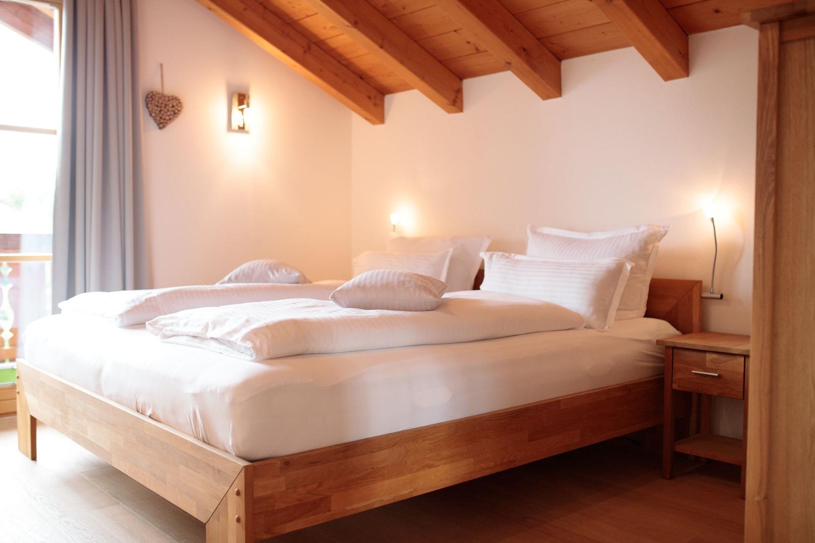 Ein Schlafzimmer mit Holzbett, Nachttisch und Deckenbalken.