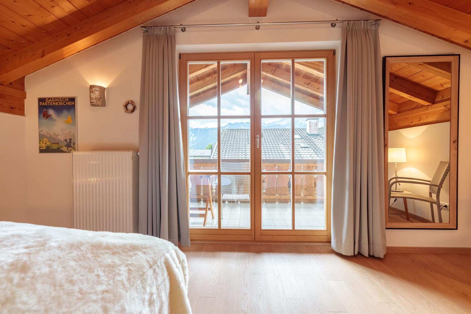 Schlafzimmer mit Blick auf Balkon und Berge. Holzdecke und Boden.