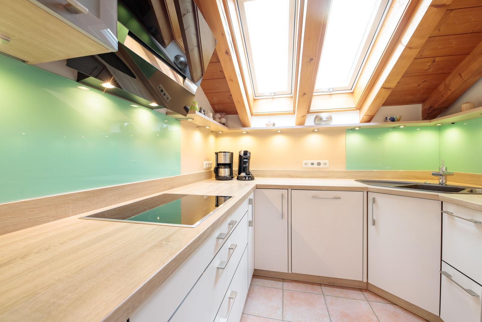 Küche mit Holzdecke, grüner Rückwand und Edelstahlgeräten.
