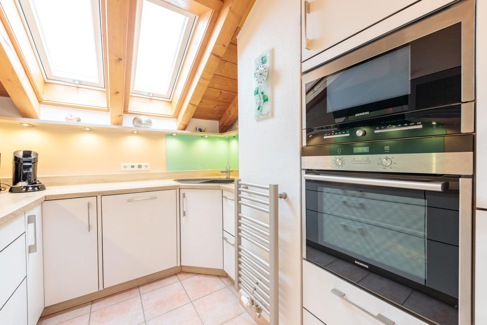 Küche mit integriertem Ofen und Dunstabzugshaube unter Dachschrägen.
