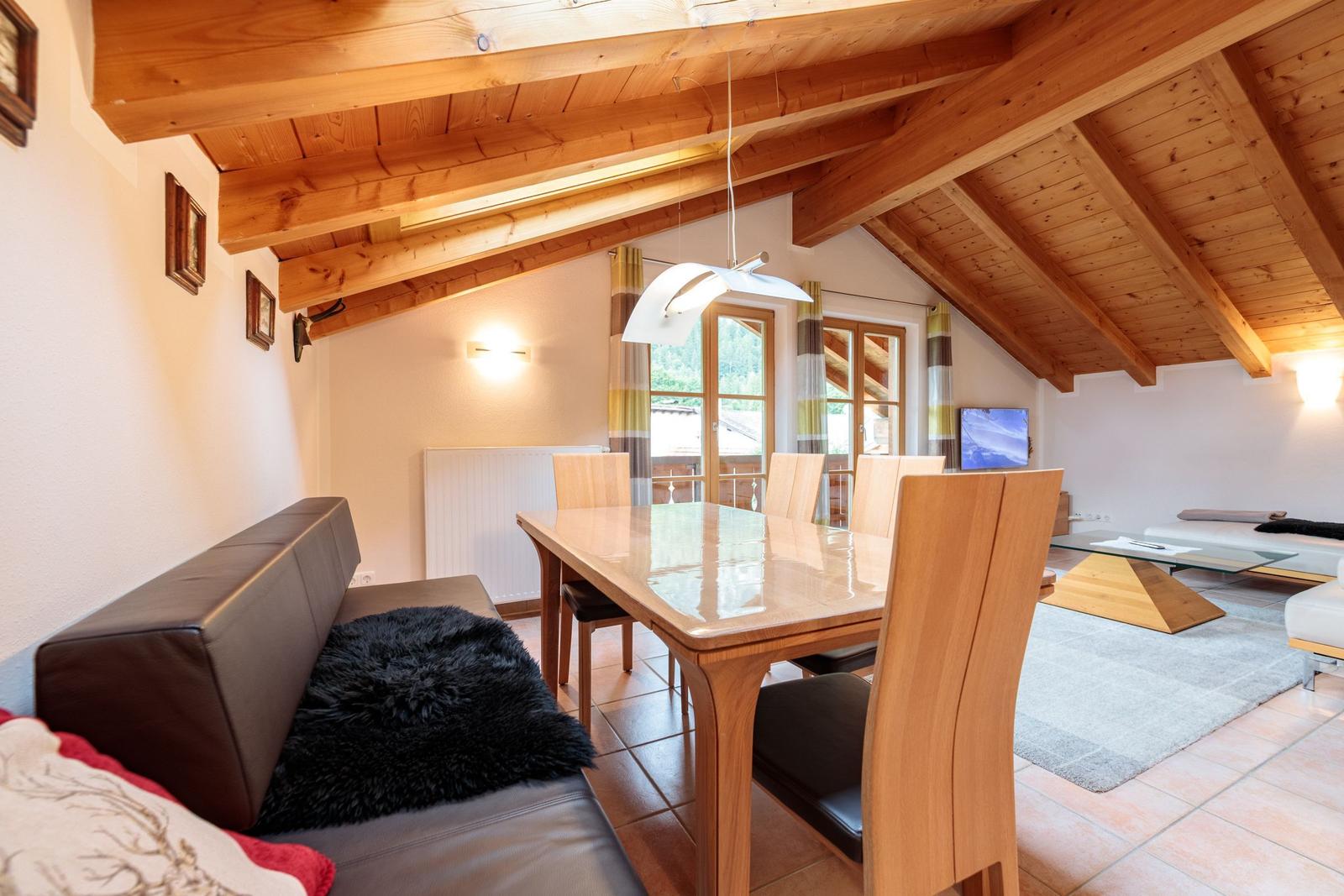 Wohn- und Essbereich mit Holzdecke, Esstisch und Sofa.