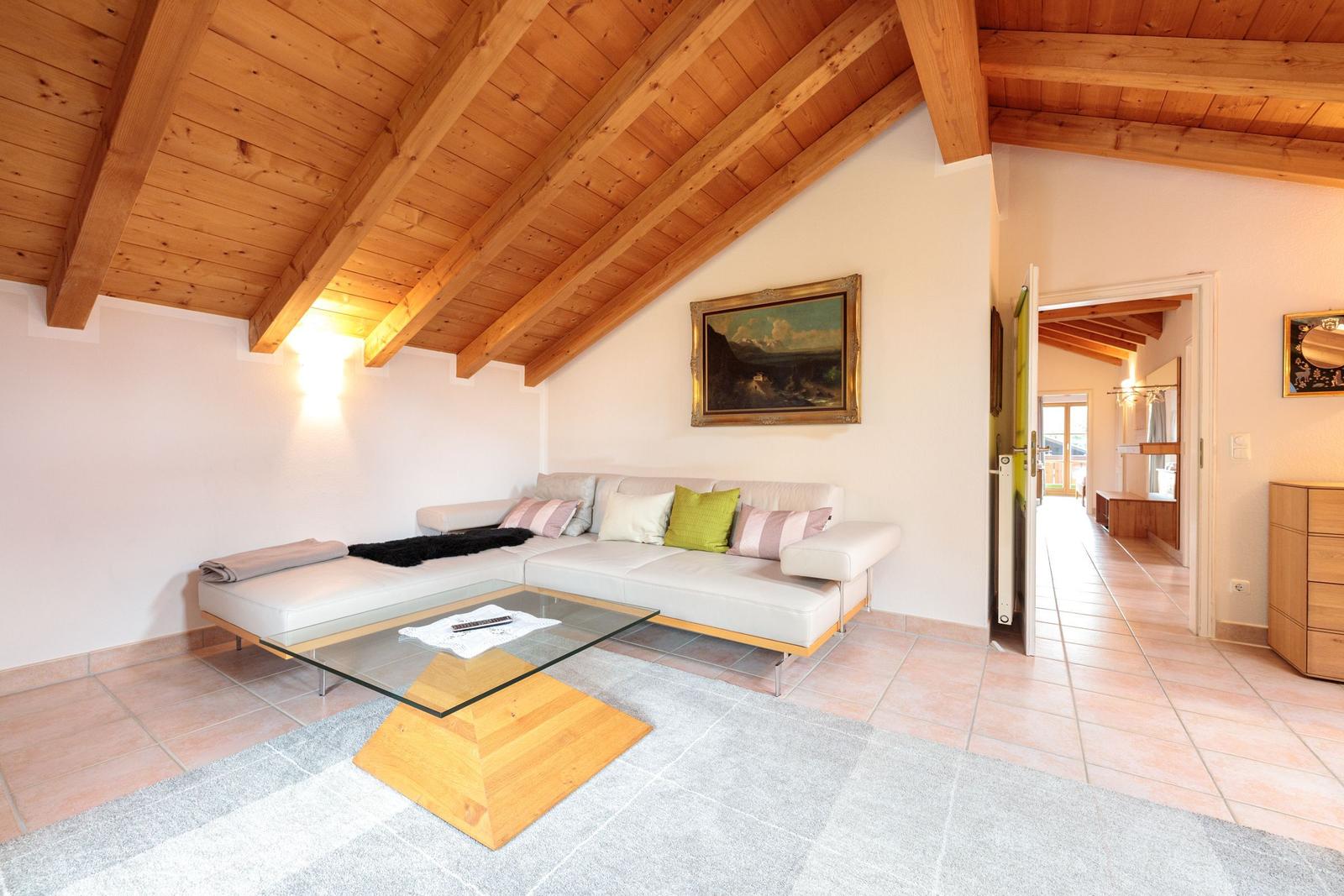 Wohnzimmer mit Sofa, Glas-Tisch und Holzdecke