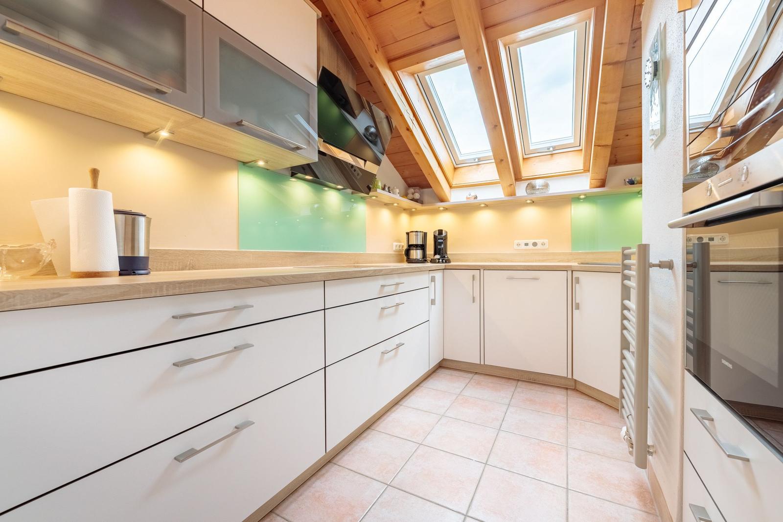 Küche mit Holzdecke, Dachfenstern und hellen Arbeitsplatten.