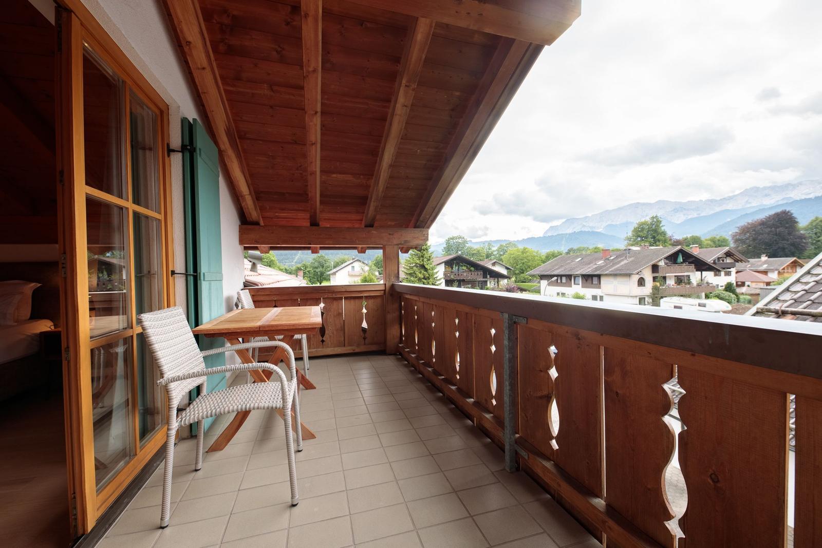Terrasse mit Tisch, Stühlen und Blick auf Berglandschaft.
