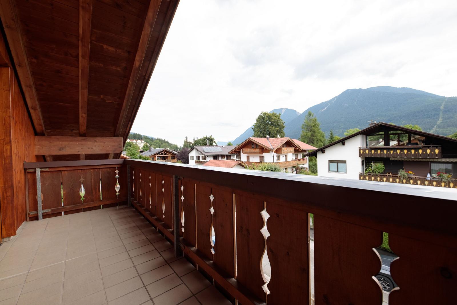 Terrasse mit Holzgeländer und Blick auf Berge und Häuser