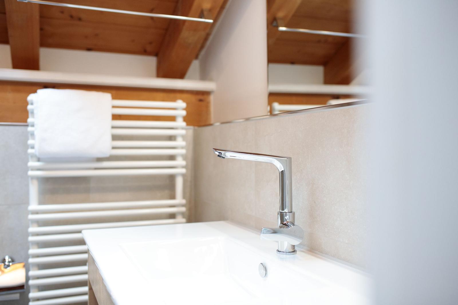 Waschbecken mit Wasserhahn und Handtuchhalter unter Holzdecke