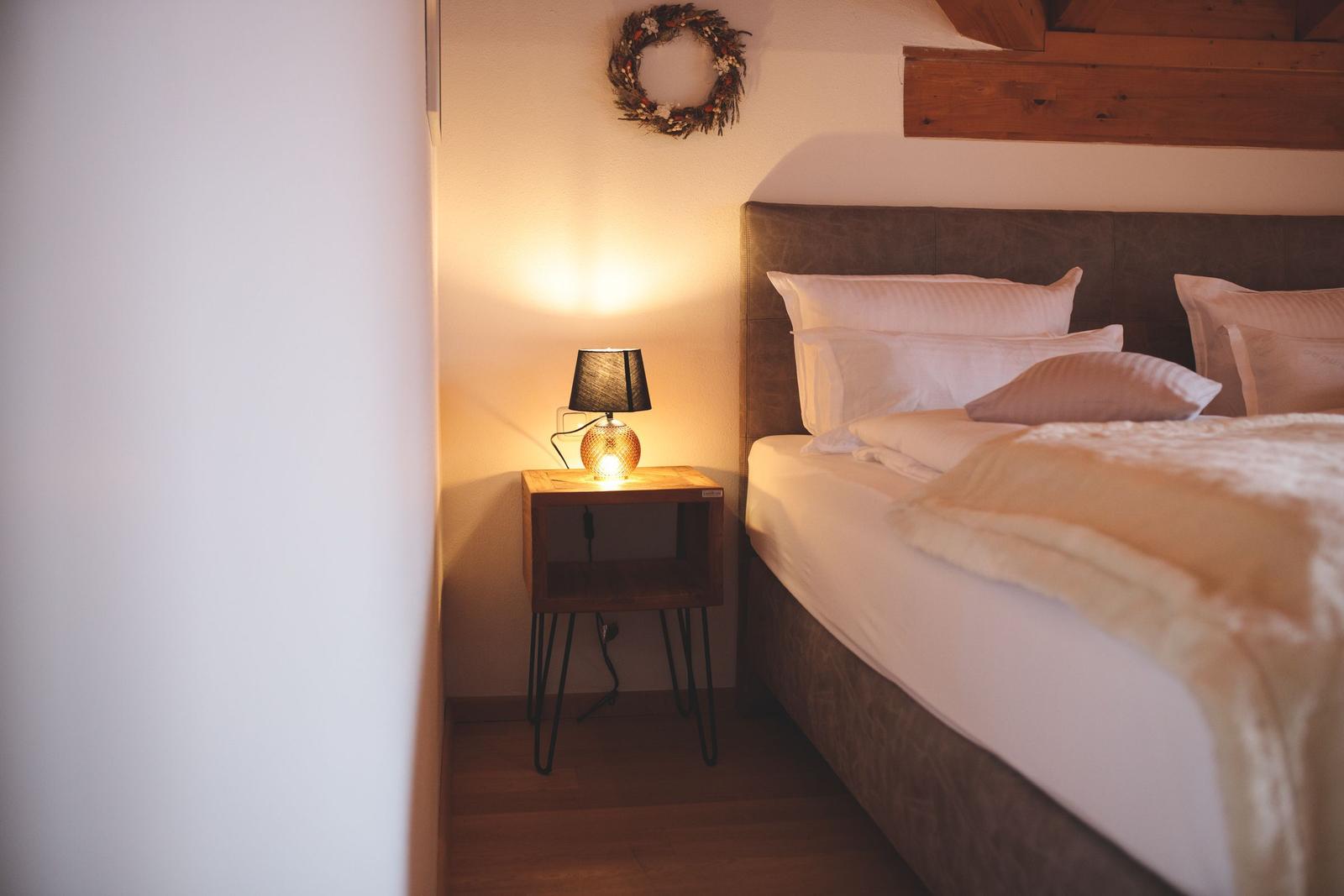 Schlafzimmer mit Bett, Nachttisch und Lampe. Wanddekoration und Holzkonstruktion.